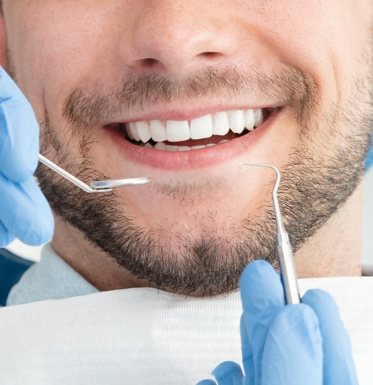 patient smiling as dentist uses tools to observe his teeth